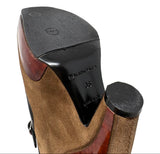 Close-up of the sole of a Balenciaga high-heeled shoe, showing a black textured rubber outsole, a glossy black heel counter with the Balenciaga brand name and size 36 printed on it, and a brown suede and reddish-brown wood-look upper.