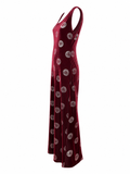 A sleeveless halter-neck maxi dress in deep burgundy velvet with an allover circular medallion pattern, shown from a side profile view against a plain white background.