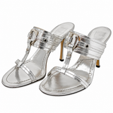 A pair of metallic silver T-strap high-heeled sandals with buckle straps and gold-tone heels, shown on a plain white background.
