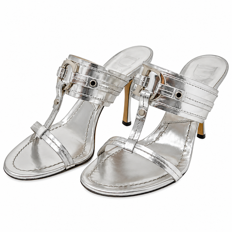 A pair of metallic silver T-strap high-heeled sandals with buckle straps and gold-tone heels, shown on a plain white background.
