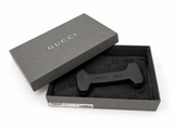A black Gucci dog-shaped shoe tree displayed inside its open dark gray Gucci gift box, with the brand name 'GUCCI' visible on the lid and embossed on the dog tree.