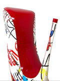 Close-up of the Louboutin heel and stiletto heel of a high-top sneaker, featuring a glossy red sole and a white upper decorated with colorful graffiti-style drawings.