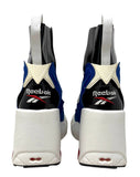 A pair of Margiela x Reebok high-top sneakers shown from the back, featuring a white platform sole, a black heel counter, blue overlays, and a cream star logo.