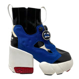 A platform sneaker boot featuring a bold blue and black upper, a chunky white platform sole, and a red accent on the heel, with a circular 'Insta Pump' patch attached.