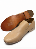 A pair of men's slip-on leather shoes in tan, with one shoe showing the side profile and the other showing the brown leather sole.