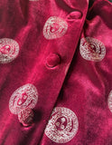 A close-up of a deep magenta velvet fabric with white embroidered circular Medusa-style motifs and matching fabric-covered buttons.