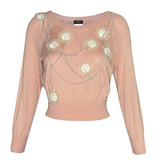 A pale pink long Chanel sleeve knit top with circular metallic embellishments and draped chain details on the front, shown against a plain white background.