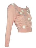A pale pink Chanel long-sleeve knit top with decorative circular white patches and thin metallic wire details on the front, shown against a plain white background.
