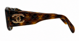Chanel sunglasses featuring a dark brown and black tortoiseshell acetate frame with a gold-tone interlocking CC logo on the temple, set against a plain white background.