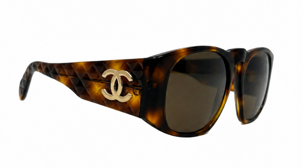 Chanel sunglasses with a brown and black tortoiseshell pattern, featuring a woven leather detail on the temple and a gold-tone interlocking CC logo.