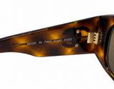 Close-up of a tortoiseshell acetate sunglasses arm with gold-tone metal hinge and engraved 'MADE IN ITALY' text on a white background.