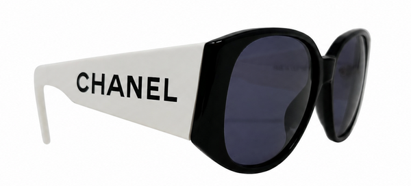Chanel sunglasses with a bold black and white frame and dark lenses, featuring the CHANEL logo printed on the white temple arm, set against a plain white background.