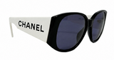 Chanel sunglasses with a white and black frame and dark blue lenses, shown on a plain white background.