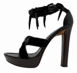 A black high-heeled platform sandal with a fuzzy ankle strap and three sharp claw-like embellishments, shown from a side profile on a white background.