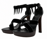 Yves Saint Laurent Black platform high-heeled sandals with crisscross straps, a mink ankle strap, and sharp claw-like embellishments on the strap, shown against a plain white background.